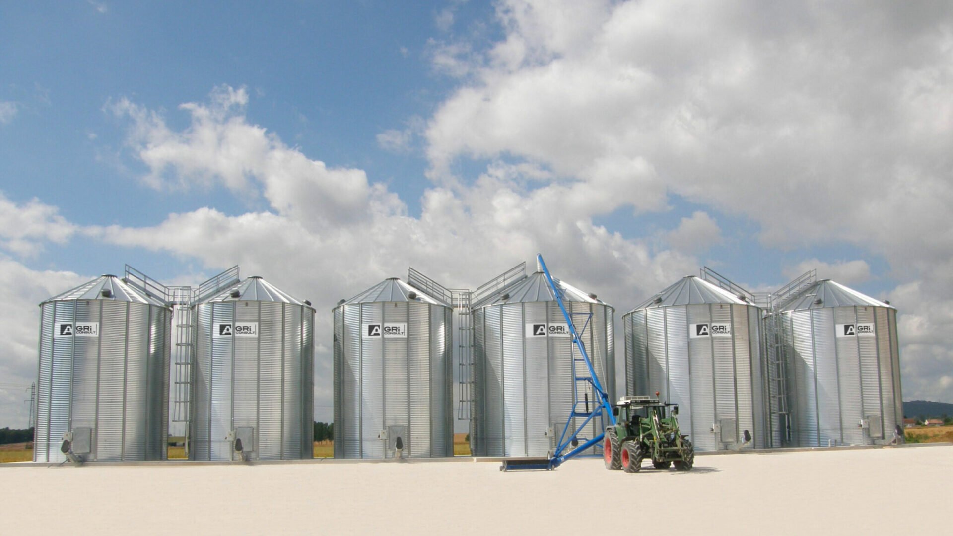 tracteur vu de face avec vis sur chariot swing away devant 6 silos à grains fond plat