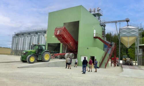 installation clé en main Agriconsult ciel bleu extérieur bâtiment photovoltaïque tracteur John Deere déchargement benne boisseau céréales grains silos cellules fond conique