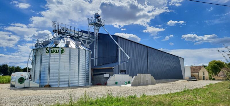 cellule sécheuse sukup agriconsult en extérieur devant batiment avec manutention gamme industrielle et fosse passante avec trémie 3 pentes pré-nettoyeur et ventilateur installation complète